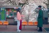 お別れの挨拶をする桜の下のバス停