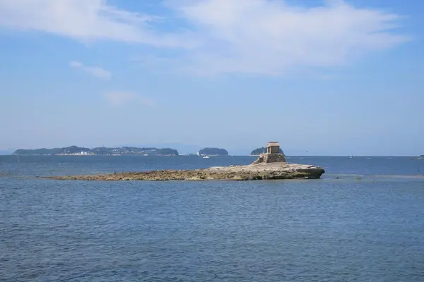 沖の岩場に祠が建っている