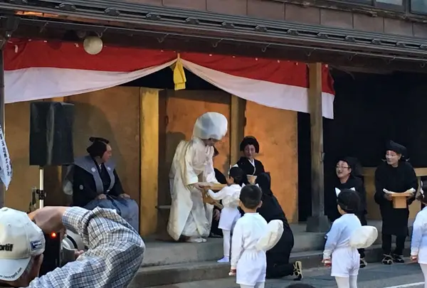 子ぎつねが花嫁さんに特大油揚げを贈呈しているところです